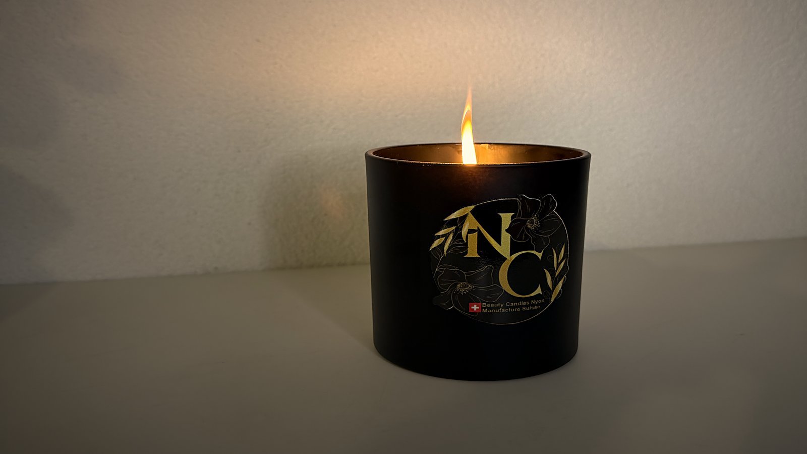 Bougie NC Candles allumée dans l'atelier de Nyon, sa flamme et sa lueur chaude